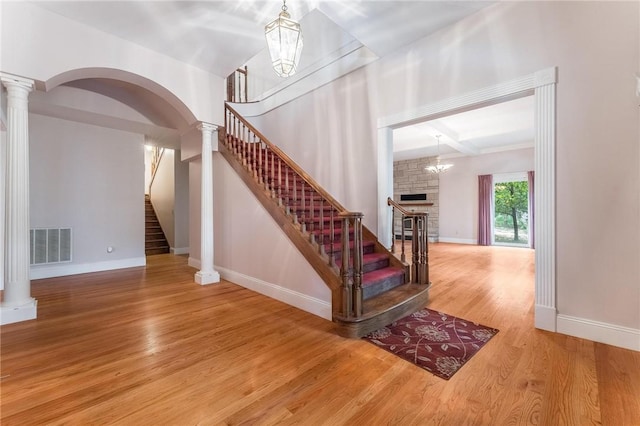 14074 Old Mill Rd, Elkins, AR 72727 - stairway featuring a fireplace, wood finished floors, ornate columns, arched walkways, and beam ceiling