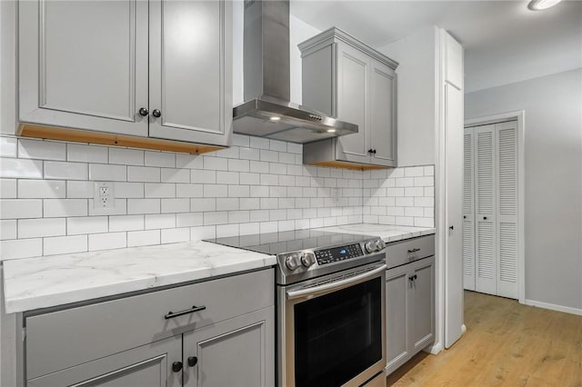 25 Grisham Cir, Bella Vista, AR 72715 - kitchen featuring wall chimney range hood, stainless steel range with electric stovetop, gray cabinetry, and light wood-style floors