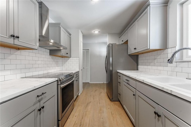 25 Grisham Cir, Bella Vista, AR 72715 - kitchen with stainless steel appliances, wall chimney range hood, gray cabinets, light wood-type flooring, and light stone countertops