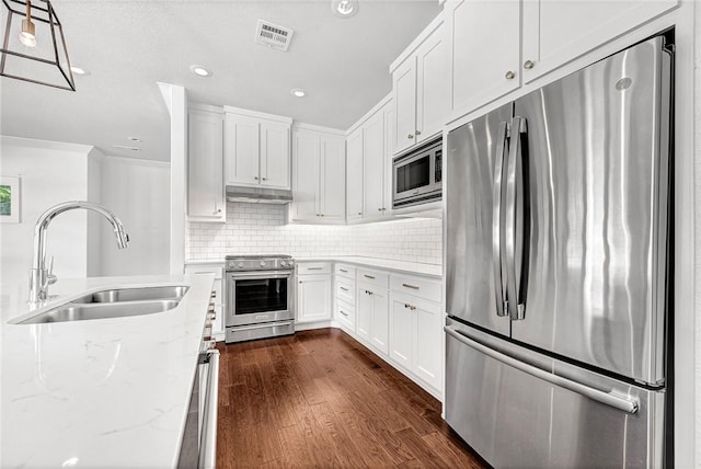 464 Block Ave, Fayetteville, AR 72701 - kitchen with stainless steel appliances, under cabinet range hood, light stone countertops, dark wood-type flooring, and decorative backsplash