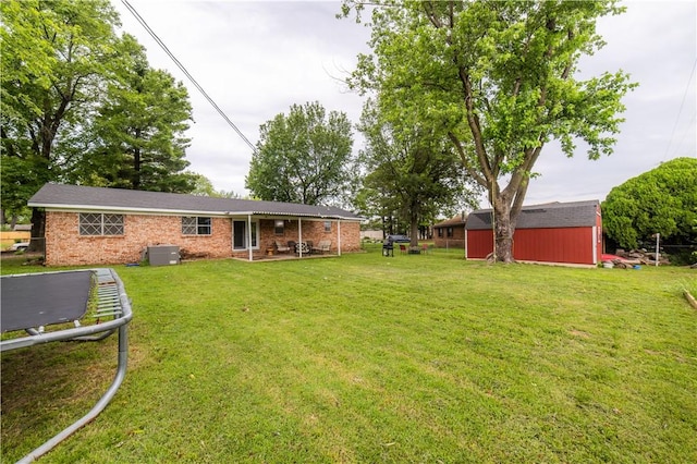 805 S Oak Hill St, Siloam Springs, AR 72761 - rear view of property featuring a storage shed, a lawn, a trampoline, and brick siding