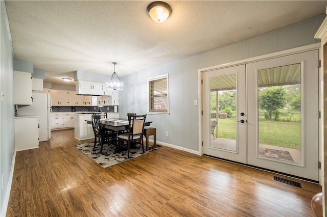 805 S Oak Hill St, Siloam Springs, AR 72761 - dining space featuring a chandelier, french doors, wood finished floors, and a textured ceiling