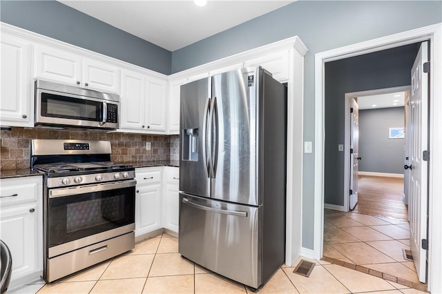 13449 Loyle Ln, Gravette, AR 72736 - kitchen featuring appliances with stainless steel finishes, light tile patterned floors, white cabinets, decorative backsplash, and dark stone countertops