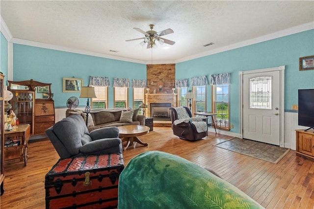 617 County Road 736, Berryville, AR 72616 - living area featuring hardwood / wood-style flooring, a stone fireplace, a ceiling fan, crown molding, and a textured ceiling