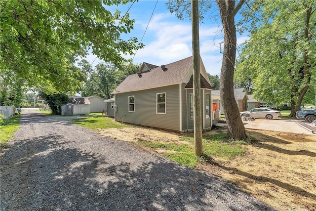 408 SW 2nd Ave, Gravette, AR 72736 - view of side of home featuring a storage unit and driveway