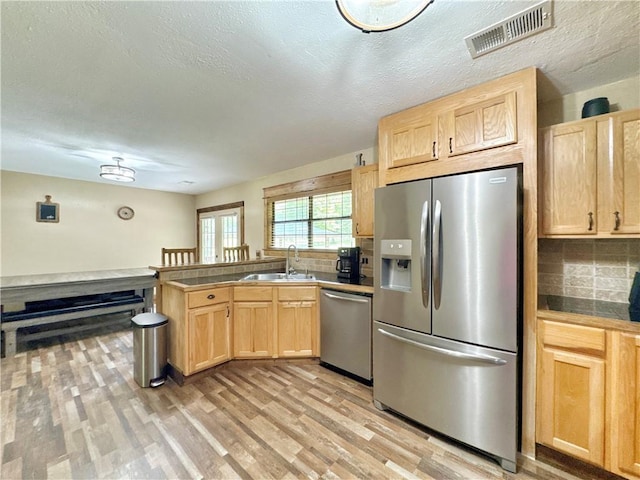 8500 Rock Creek Rd, Mulberry, AR 72947 - kitchen with stainless steel appliances, light brown cabinetry, a peninsula, backsplash, and a textured ceiling
