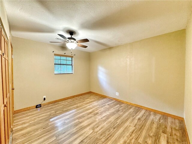 8500 Rock Creek Rd, Mulberry, AR 72947 - unfurnished room with light wood finished floors, a ceiling fan, and a textured ceiling