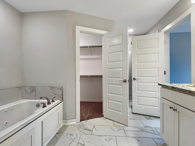 217 Idaho Ave, Farmington, AR 72730 - bathroom with marble look tile flooring, a jetted tub, vanity, a walk in closet, and recessed lighting