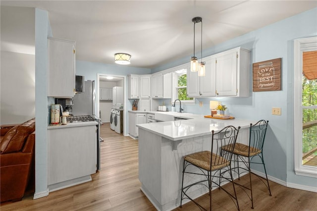 16590 Roughton Ln, Pea Ridge, AR 72751 - kitchen featuring washer / dryer, a peninsula, white cabinetry, and plenty of natural light