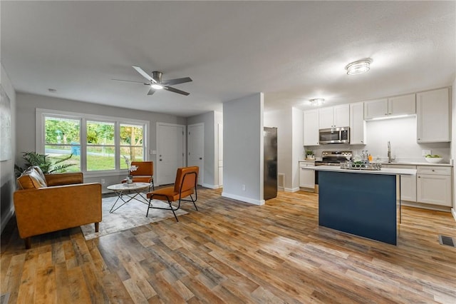 2 Rochdale Dr, Bella Vista, AR 72714 - kitchen with stainless steel appliances, open floor plan, white cabinetry, a ceiling fan, and light wood-style floors