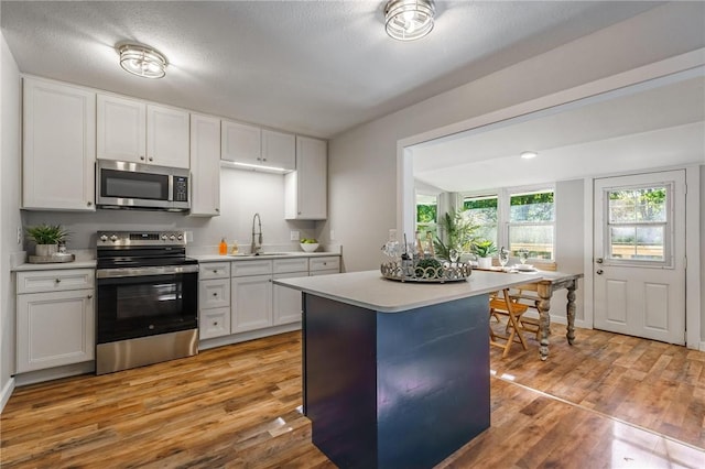 2 Rochdale Dr, Bella Vista, AR 72714 - kitchen with stainless steel appliances, light countertops, light wood finished floors, and white cabinets