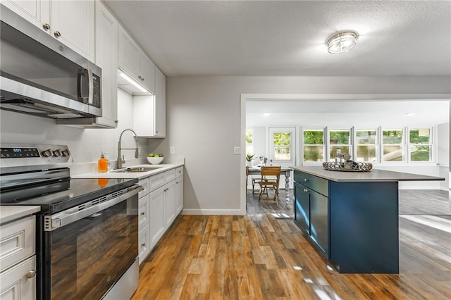 2 Rochdale Dr, Bella Vista, AR 72714 - kitchen with stainless steel appliances, wood-type flooring, white cabinetry, and light countertops