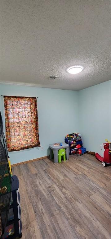 1210 Spring St, Bentonville, AR 72712 - playroom featuring wood finished floors and a textured ceiling