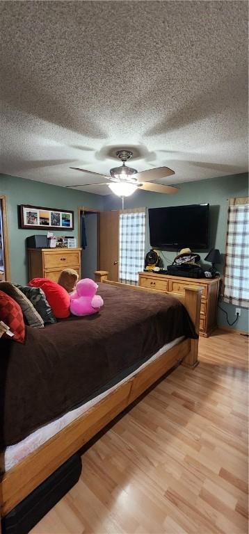 1210 Spring St, Bentonville, AR 72712 - bedroom with a textured ceiling, light wood-type flooring, and a ceiling fan