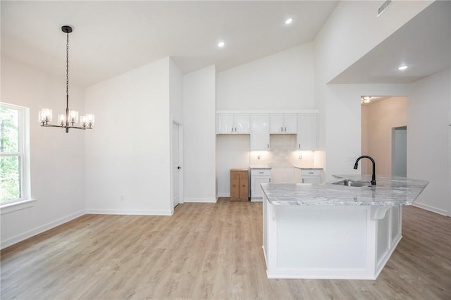 7 Consett Ln, Bella Vista, AR 72714 - kitchen featuring white cabinets, high vaulted ceiling, light wood-type flooring, decorative backsplash, and a center island with sink