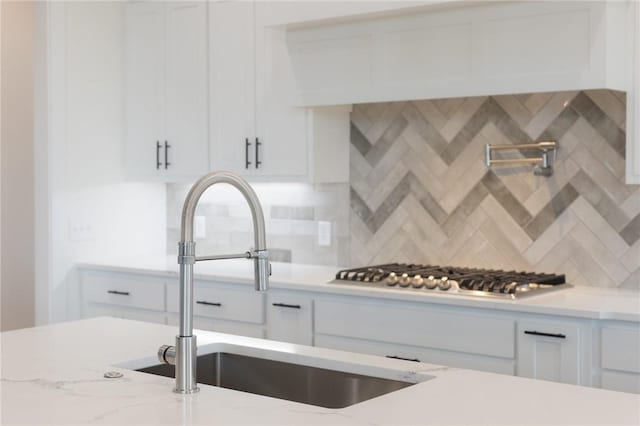 8607 W Feathered Nest Run, Bentonville, AR 72713 - kitchen with stainless steel gas stovetop, white cabinetry, decorative backsplash, and light stone counters
