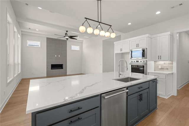 8607 W Feathered Nest Run, Bentonville, AR 72713 - kitchen with stainless steel appliances, a fireplace, a ceiling fan, light wood finished floors, and recessed lighting