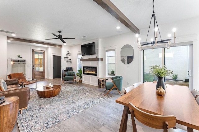 103 NW Ozark Way, Bentonville, AR 72712 - living room with wood finished floors, a ceiling fan, a glass covered fireplace, a chandelier, and beamed ceiling