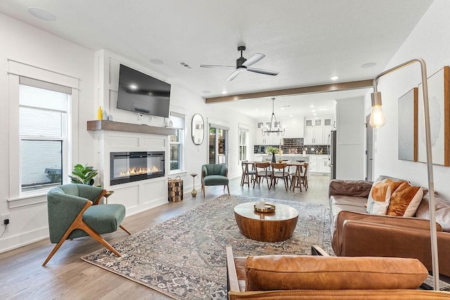 103 NW Ozark Way, Bentonville, AR 72712 - living room featuring ceiling fan, a glass covered fireplace, healthy amount of natural light, light wood finished floors, and recessed lighting