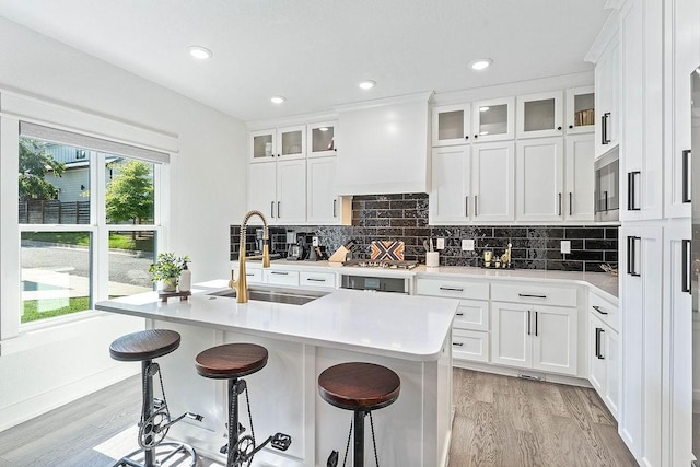 103 NW Ozark Way, Bentonville, AR 72712 - kitchen with light wood-style floors, light countertops, a breakfast bar area, tasteful backsplash, and recessed lighting