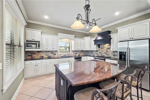 4130 Willowbend Dr, Rogers, AR 72758 - kitchen with appliances with stainless steel finishes, custom exhaust hood, a kitchen breakfast bar, white cabinetry, and ornamental molding