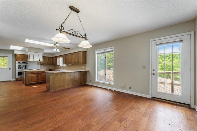 8394 Admiral Nimitz Dr, Rogers, AR 72756 - kitchen featuring double oven, brown cabinetry, a textured ceiling, dark wood-style floors, and light countertops
