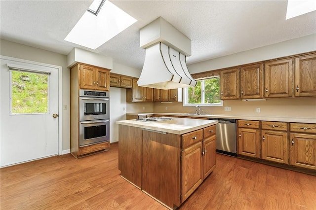 8394 Admiral Nimitz Dr, Rogers, AR 72756 - kitchen with appliances with stainless steel finishes, brown cabinets, a skylight, light countertops, and wood finished floors