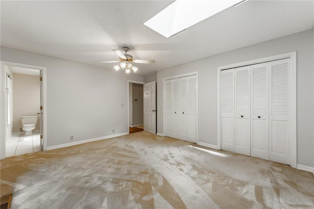 8394 Admiral Nimitz Dr, Rogers, AR 72756 - unfurnished bedroom with carpet flooring, two closets, a skylight, ensuite bathroom, and ceiling fan