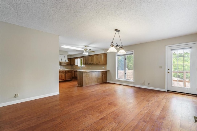 8394 Admiral Nimitz Dr, Rogers, AR 72756 - kitchen featuring light wood-style floors, a peninsula, open floor plan, brown cabinets, and a ceiling fan