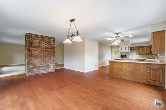 8394 Admiral Nimitz Dr, Rogers, AR 72756 - kitchen featuring open floor plan, oven, brown cabinets, wood finished floors, and a peninsula