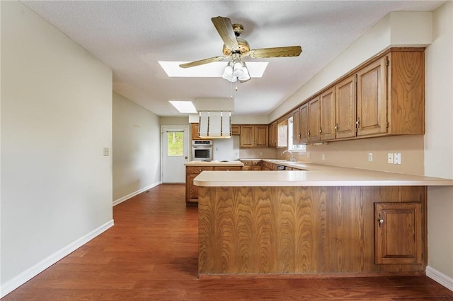 8394 Admiral Nimitz Dr, Rogers, AR 72756 - kitchen featuring a skylight, a peninsula, oven, wood finished floors, and a ceiling fan