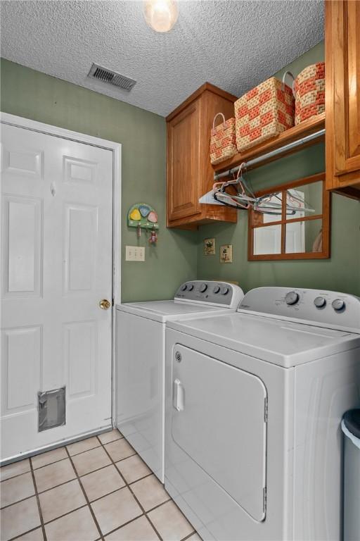 2105 Brookhaven Dr, Alma, AR 72921 - laundry area with cabinet space, washing machine and clothes dryer, a textured ceiling, and light tile patterned floors