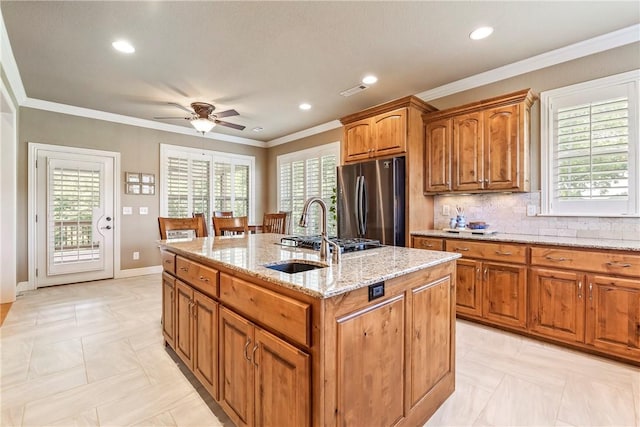 348 Whitcliff Dr, Cave Springs, AR 72718 - kitchen with freestanding refrigerator, an island with sink, light stone countertops, brown cabinets, and a ceiling fan