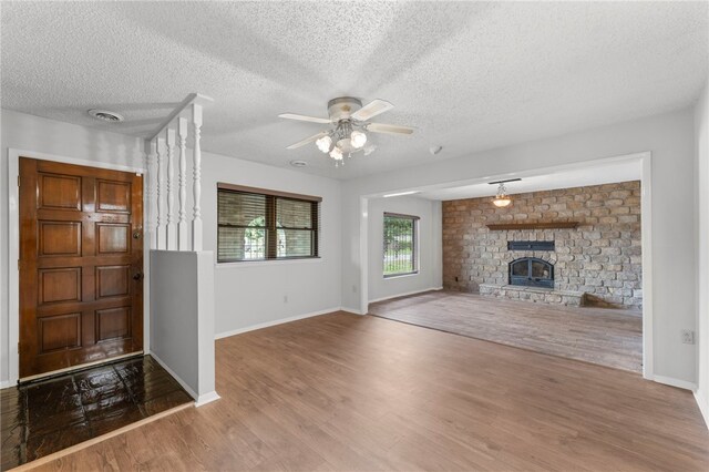 603 Thomas Blvd, Springdale, AR 72762 - unfurnished living room with wood finished floors, a textured ceiling, a ceiling fan, and a brick fireplace