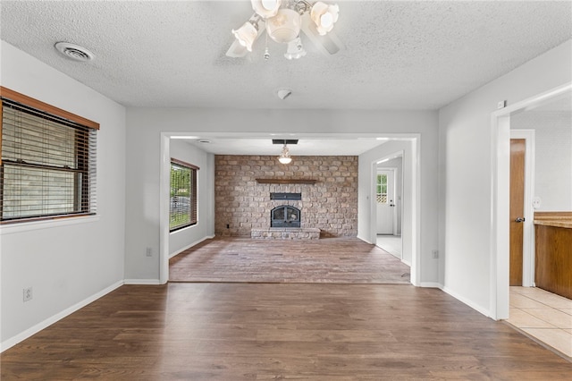 603 Thomas Blvd, Springdale, AR 72762 - unfurnished living room with wood finished floors, a textured ceiling, a ceiling fan, and a large fireplace