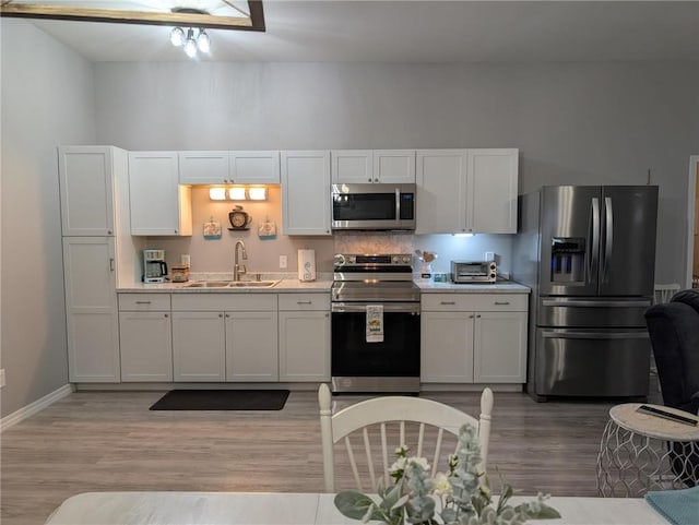 1445 Woodhaven Ln, Harrison, AR 72601 - kitchen featuring stainless steel appliances, light wood-type flooring, light countertops, and white cabinetry
