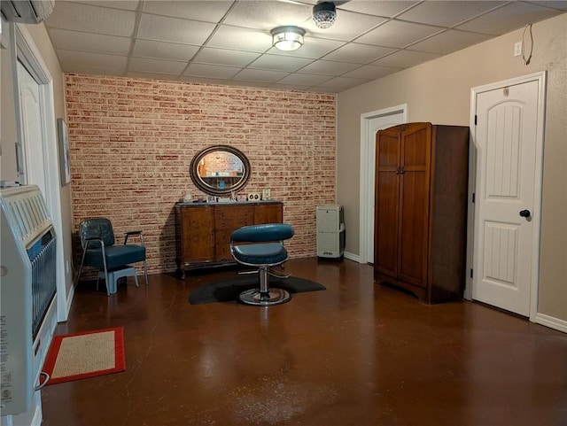 1445 Woodhaven Ln, Harrison, AR 72601 - sitting room featuring a paneled ceiling, concrete flooring, heating unit, brick wall, and a wall unit AC