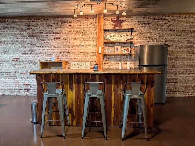 1445 Woodhaven Ln, Harrison, AR 72601 - indoor wet bar featuring freestanding refrigerator, brick wall, and concrete flooring