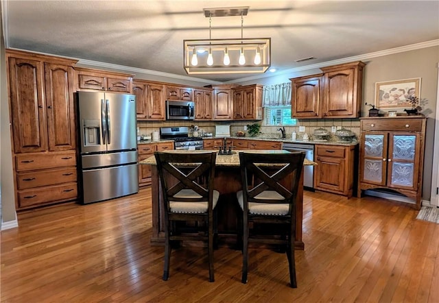 1445 Woodhaven Ln, Harrison, AR 72601 - kitchen featuring appliances with stainless steel finishes, brown cabinetry, tasteful backsplash, decorative light fixtures, and crown molding