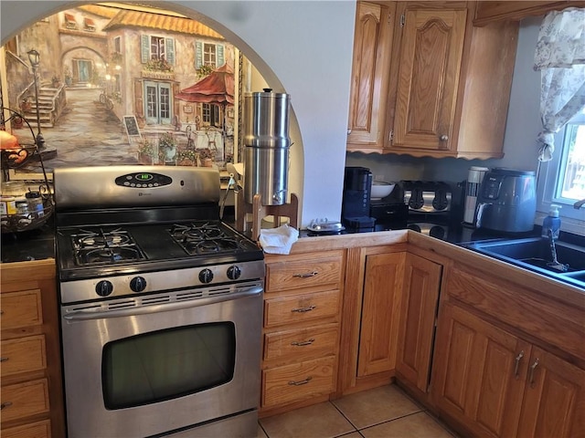 400 Franklin St, Harrison, AR 72601 - kitchen with stainless steel range with gas stovetop, arched walkways, brown cabinets, and light tile patterned floors