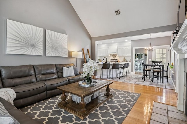 1112 N Oriole Ave, Rogers, AR 72756 - living room with high vaulted ceiling, a chandelier, and light wood finished floors