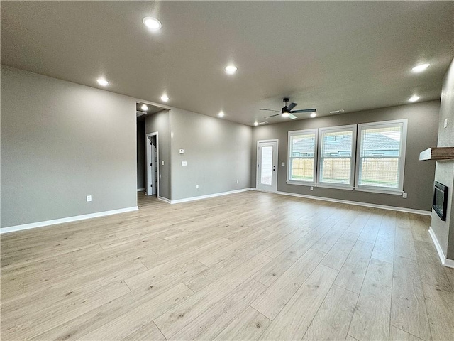 6003 SW Desert Ave, Bentonville, AR 72713 - unfurnished living room featuring ceiling fan, a glass covered fireplace, light wood-type flooring, and recessed lighting