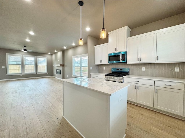 6003 SW Desert Ave, Bentonville, AR 72713 - kitchen with appliances with stainless steel finishes, a kitchen island, backsplash, white cabinets, and recessed lighting