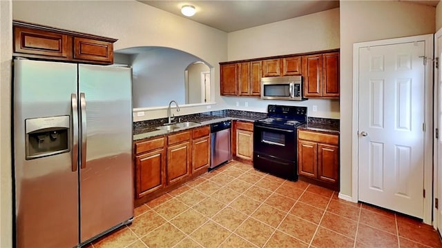 3107 SW Wentworth Ave, Bentonville, AR 72713 - kitchen with appliances with stainless steel finishes, arched walkways, light tile patterned floors, and brown cabinets