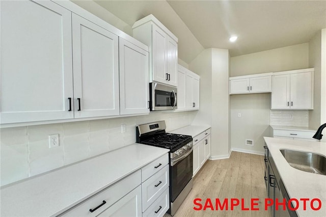 5906 SW Chiefs Rd, Bentonville, AR 72713 - kitchen featuring appliances with stainless steel finishes, decorative backsplash, white cabinets, light wood-type flooring, and recessed lighting