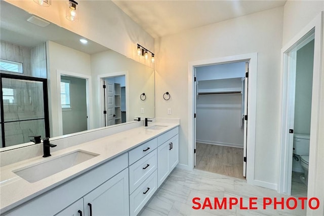 5906 SW Chiefs Rd, Bentonville, AR 72713 - bathroom with a spacious closet, double vanity, marble finish floors, and tiled shower