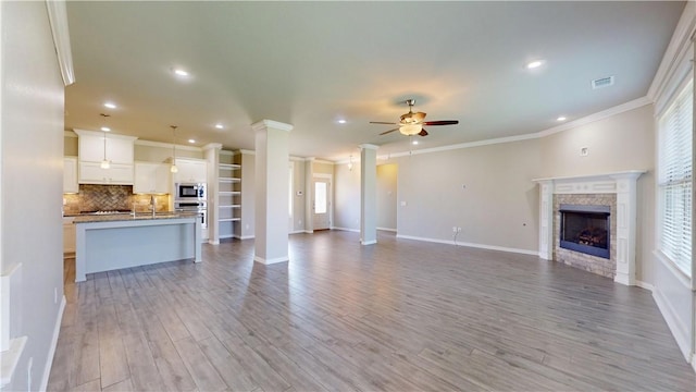1218 Bradley St, Centerton, AR 72719 - unfurnished living room with ornamental molding, a ceiling fan, decorative columns, healthy amount of natural light, and light wood finished floors