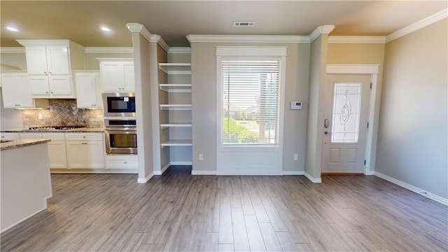 1218 Bradley St, Centerton, AR 72719 - kitchen with white cabinets, backsplash, light wood-style flooring, light stone counters, and ornamental molding