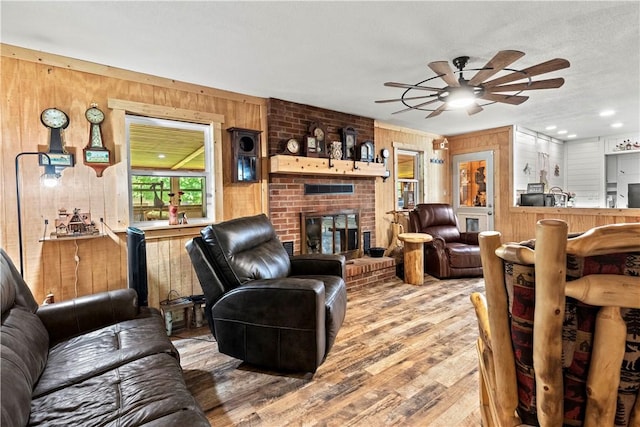 89 Creekview Rd, Harrison, AR 72601 - living room featuring wooden walls, light wood-type flooring, ceiling fan, and a brick fireplace
