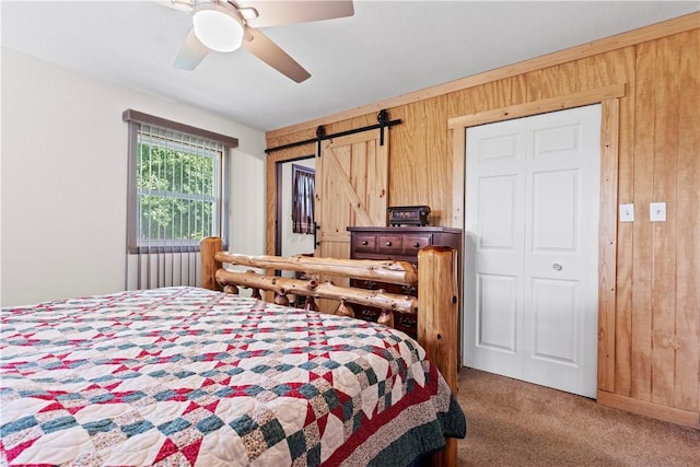 89 Creekview Rd, Harrison, AR 72601 - carpeted bedroom featuring wood walls, a barn door, and ceiling fan